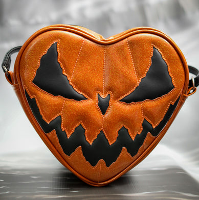 Heart shaped bag with Orange Glitter with a plain black Evil face.